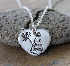 "This necklace features a handmade fine silver (99.9% pure silver) heart pendant stamped with a sweet little Totoro with a flower and a friendly soot sprite. The stamping is oxidized to make it stand out and the rest of the pendant is matte silver. The heart charm is about 7/8\" wide and 3/5\" tall (22x18mm) and is hung on a delicate sterling silver chain finished off with a sterling silver lobster clasp. I have a few other Totoro themed items in my shop. See them here: https://www.etsy.com/shop Anime Fan Art, Soot Sprite, Silver Jewelry Diy, Cleaning Silver Jewelry, Forest Spirit, Precious Metal Clay, Handmade Heart, Silver Heart Pendant, Silver Jewellery Sets