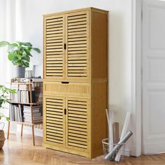 a tall wooden cabinet sitting in the corner of a room next to a potted plant