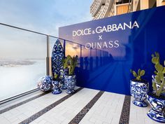 blue and white vases are sitting on the ledge near a sign that reads dolce gabbana x compass