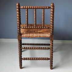 an old wooden chair sitting on top of a white floor next to a blue wall