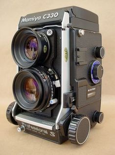 an old camera with two lenses attached to it's body and on the side