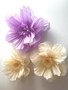 three purple and white paper flowers sitting on top of a table