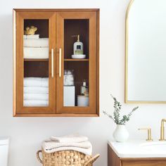 a bathroom cabinet with towels and toiletries in it next to a mirror on the wall