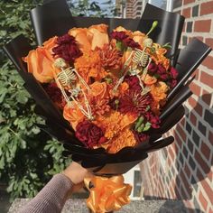 a person holding a bouquet of flowers with skeleton decorations on it's head and hands