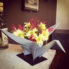 a vase filled with yellow and red flowers on top of a table next to a bottle