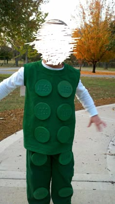 a young boy dressed in a costume made to look like a lego man standing on a sidewalk