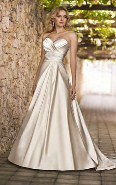 a woman in a wedding dress standing by a stone wall