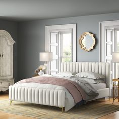 a large white bed sitting in a bedroom on top of a hard wood floor