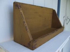 an old wooden box sitting on top of a white shelf next to a window sill