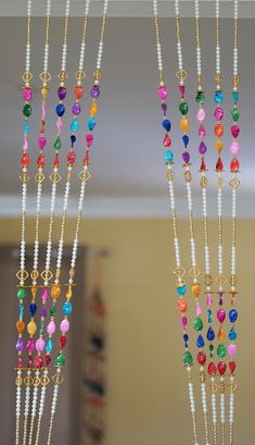 three necklaces hanging from the ceiling with beads and other items on display in front of them