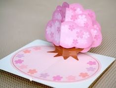 a pink paper flower on top of a card