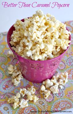 a pink bowl filled with popcorn sitting on top of a table