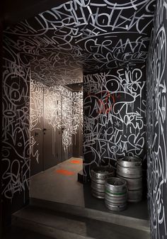 graffiti is painted on the walls in an industrial room with metal barrels and steel doors