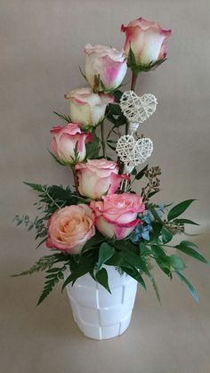 a white vase filled with lots of pink and white flowers