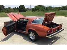 an orange car with its hood open and it's trunk opened in the driveway