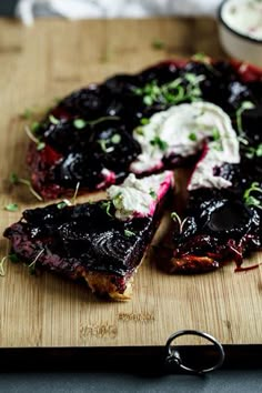 a wooden cutting board topped with slices of pie covered in blueberry compote