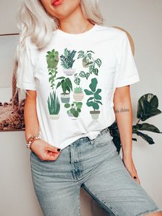 a woman with blonde hair wearing a white t - shirt with green plants on it