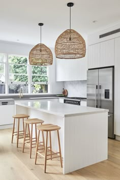 a kitchen with white cabinets and wooden stools next to an island in the middle