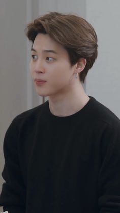 the young man is wearing a black sweater and looking off to the side with his eyes closed