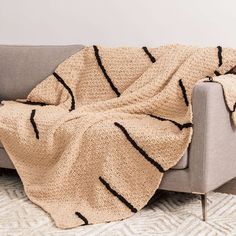 a couch with a blanket on top of it next to a white rug and wall