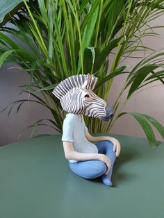 a zebra figurine sitting on top of a green table next to a potted plant