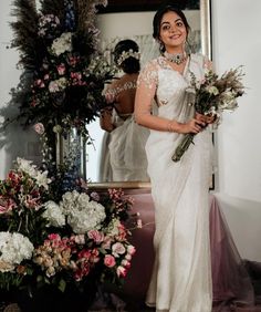 a woman standing in front of a mirror holding flowers