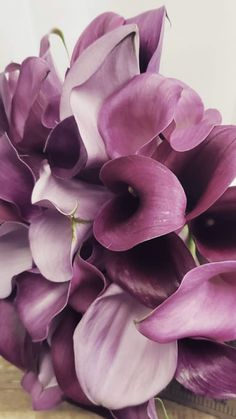 a bouquet of purple flowers sitting on top of a wooden table