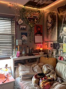 a messy bedroom with posters on the wall and lights strung from the ceiling above it