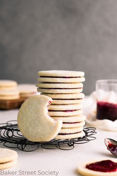 a stack of cookies sitting on top of a table next to jams and spoons