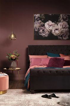 a bedroom with purple walls and pink bedding in the corner, along with a large floral painting on the wall