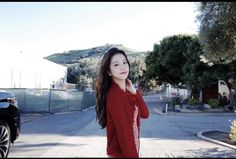 a woman standing on the side of a road next to a car