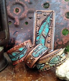 three leather bracelets sitting on top of a wooden table next to a metal object