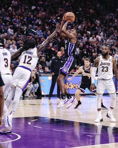 the basketball players are trying to block the ball from going into the basket as the crowd looks on