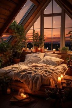 a bed with blankets and candles on top of it in front of a window filled with potted plants