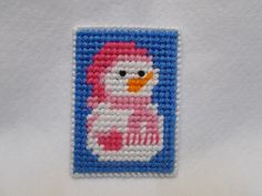 a needled picture of a pink and white bird with blue trim on a white shirt