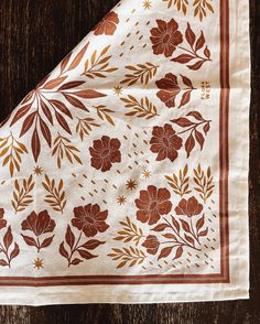 a brown and white floral design on a wooden table cloth with gold trimmings