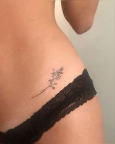 a woman's stomach with a small flower tattoo on her left side ribcage