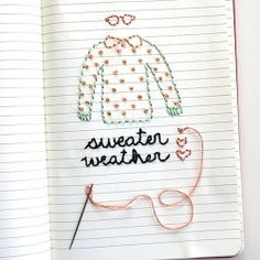 a notebook with an embroidered sweater and knitting needles on it next to a pair of scissors