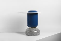 a blue glass vase sitting on top of a white table next to a silver object