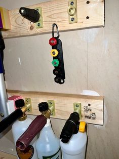 two bottles are hanging on the wall with pegs and hooks attached to it, along with other items