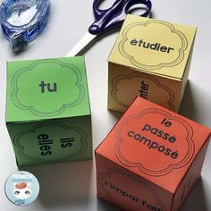 three cubes with words on them sitting next to scissors and tape measure labels that spell out the word tu