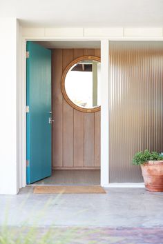 a blue door with a round window and potted plants