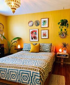 a bedroom with yellow walls, blue and white bedspread and pictures on the wall