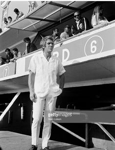 an older man standing on the side of a boat in front of people watching him