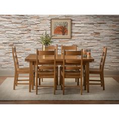 a dining room table with chairs and a rug on the floor in front of a brick wall