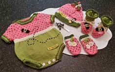 a crocheted baby outfit and booties are on a plate with other items