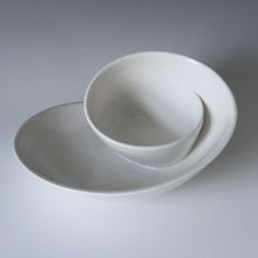 two white bowls stacked on top of each other in front of a gray background,