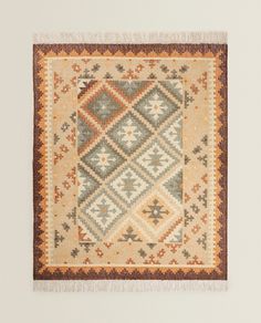 an old rug hanging on the wall with fringes around it's edges and bottom corner