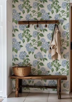 a wooden bench sitting next to a wall covered in blue and green floral wallpaper