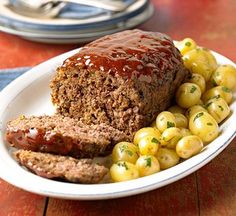 meatloaf with corn on the cob and ketchup is served on a white plate